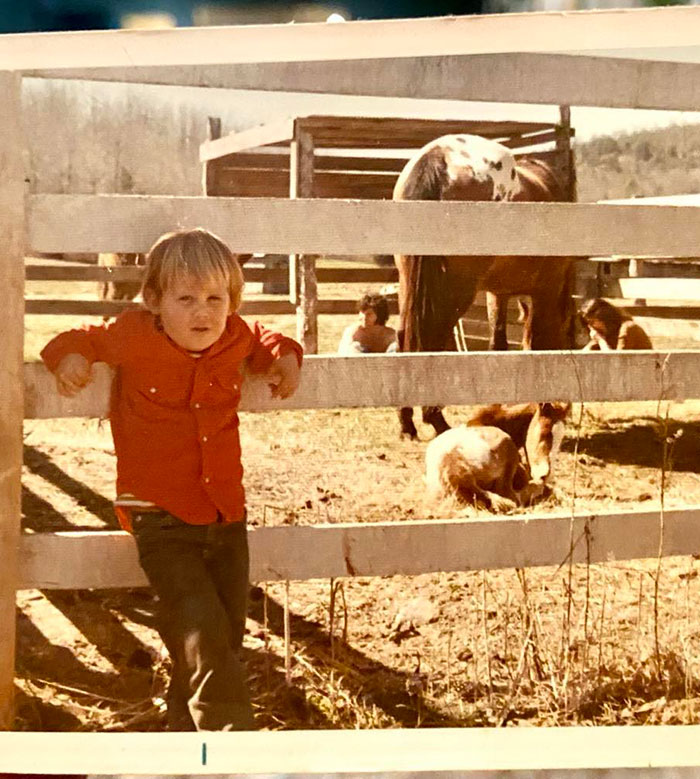 Child in orange jacket by a wooden fence with animals, related to Josh Brolin's wildlife stories. Child in orange jacket by a wooden fence with animals, related to Josh Brolin's wildlife stories.