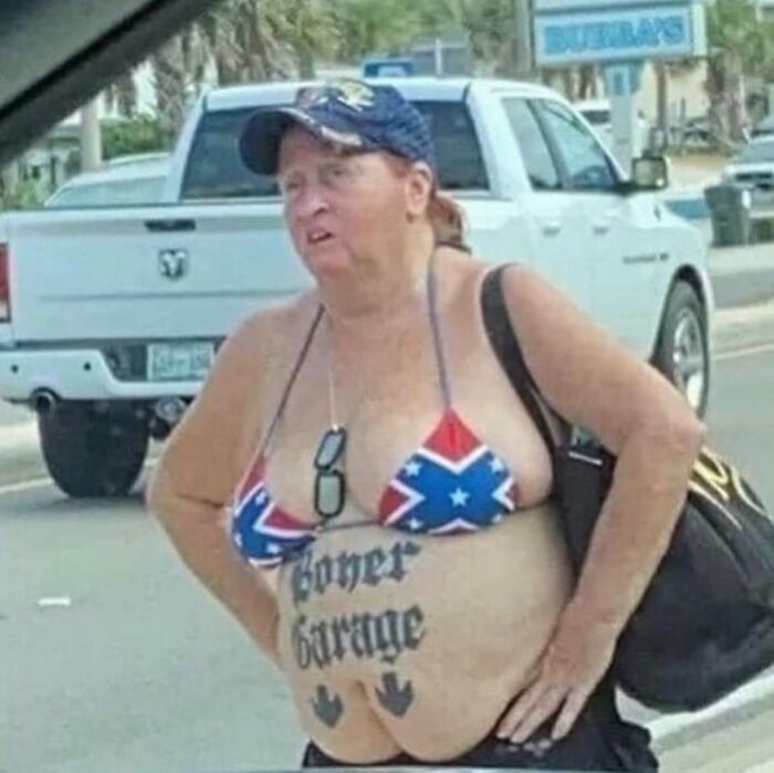 A person on the street displaying epic tattoo fails, wearing a swimsuit and holding a bag. A person on the street displaying epic tattoo fails, wearing a swimsuit and holding a bag.