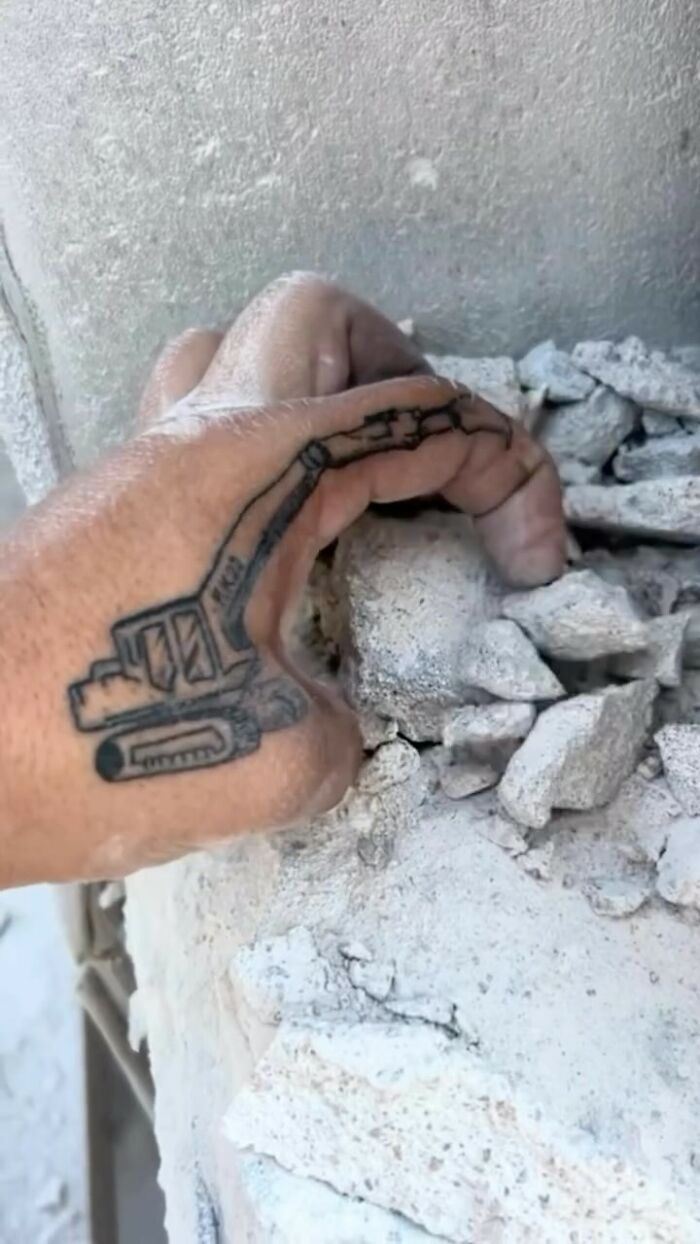Hand with an excavator tattoo, appearing to dig into concrete rubble, representing an epic tattoo fail shared online. Hand with an excavator tattoo, appearing to dig into concrete rubble, representing an epic tattoo fail shared online.