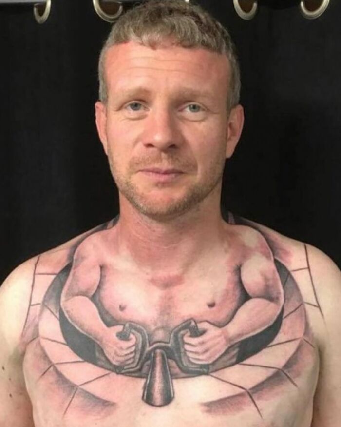 Man with tattoo fail depicting a muscular figure holding handles on his chest. Man with tattoo fail depicting a muscular figure holding handles on his chest.