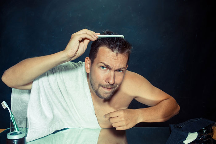 Man with towel combing hair, humorous expression. Man with towel combing hair, humorous expression.