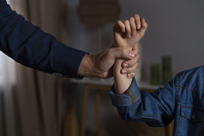 Adult holding a child’s wrist in a home setting, highlighting challenges with autistic son's aggression. Adult holding a child’s wrist in a home setting, highlighting challenges with autistic son's aggression.