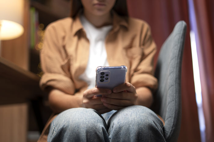 Woman sitting on chair holding phone, feeling uncomfortable in a room themed with Japanese culture. Woman sitting on chair holding phone, feeling uncomfortable in a room themed with Japanese culture.