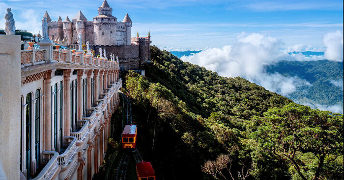Scenic view of Da Nang with a castle-like structure, lush green mountains, and a red funicular train on year-end experiences.