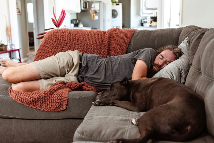 Man sleeping on the couch with a dog, illustrating a husband in an intimate home setting. Man sleeping on the couch with a dog, illustrating a husband in an intimate home setting.
