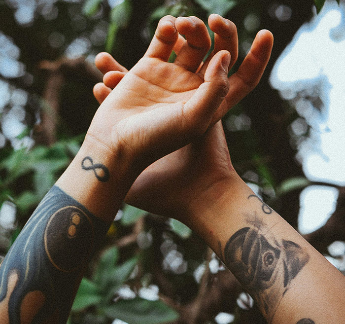 Young person's arms with tattoos in nature, illustrating tattoo trends debate. Young person's arms with tattoos in nature, illustrating tattoo trends debate.