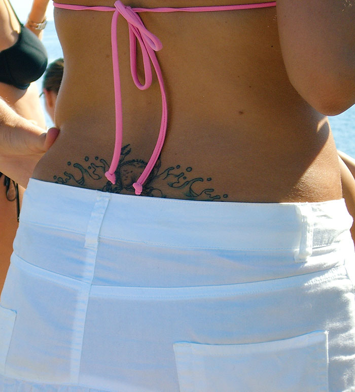 Lower back tattoo with a sea-themed design, visible above white shorts, representing 2024 tattoo trends among youth. Lower back tattoo with a sea-themed design, visible above white shorts, representing 2024 tattoo trends among youth.
