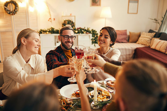 People toasting drinks at a festive dinner gathering, creating a cheerful and celebratory atmosphere. People toasting drinks at a festive dinner gathering, creating a cheerful and celebratory atmosphere.