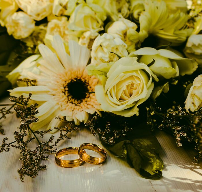 Wedding rings on a table with white roses, symbolizing commitment and marriage. Wedding rings on a table with white roses, symbolizing commitment and marriage.