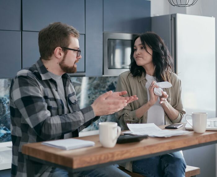Woman frustrated with partner's lack of commitment, sitting at kitchen table having an intense discussion. Woman frustrated with partner's lack of commitment, sitting at kitchen table having an intense discussion.