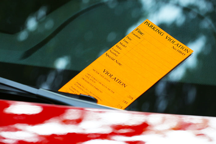 Parking violation ticket on a car windshield, highlighting improper use of handicapped spots by an officer. Parking violation ticket on a car windshield, highlighting improper use of handicapped spots by an officer.