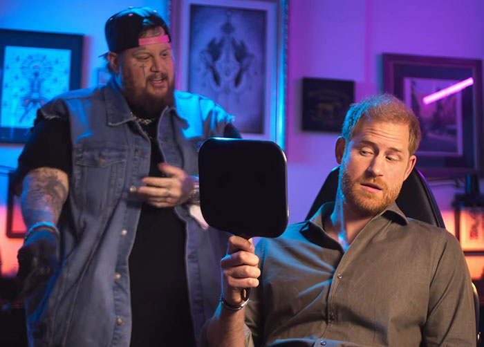Prince Harry observes neck tattoo by tattoo artist in colorful studio, expressing thoughtful demeanor. Prince Harry observes neck tattoo by tattoo artist in colorful studio, expressing thoughtful demeanor.
