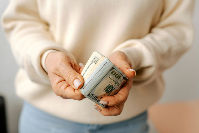 Person holding a stack of dollar bills, symbolizing refusing to pay rent. Person holding a stack of dollar bills, symbolizing refusing to pay rent.