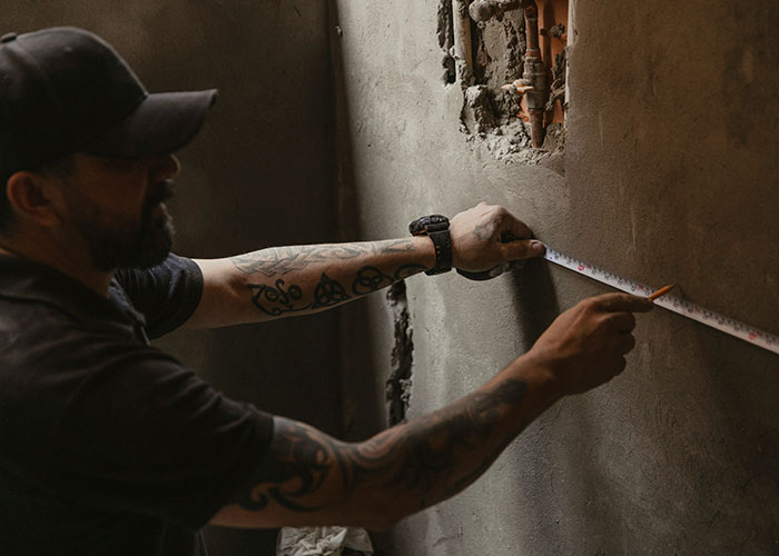 Man in black cap measuring wall for condo renovations. Man in black cap measuring wall for condo renovations.