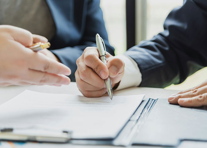 Hands signing a contract, symbolizing condo renovation dispute and landlord issues. Hands signing a contract, symbolizing condo renovation dispute and landlord issues.