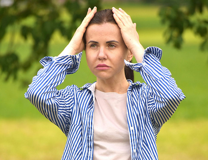 Woman in a striped shirt looking concerned outdoors, related to neighbor's private pond incident lawsuit. Woman in a striped shirt looking concerned outdoors, related to neighbor's private pond incident lawsuit.