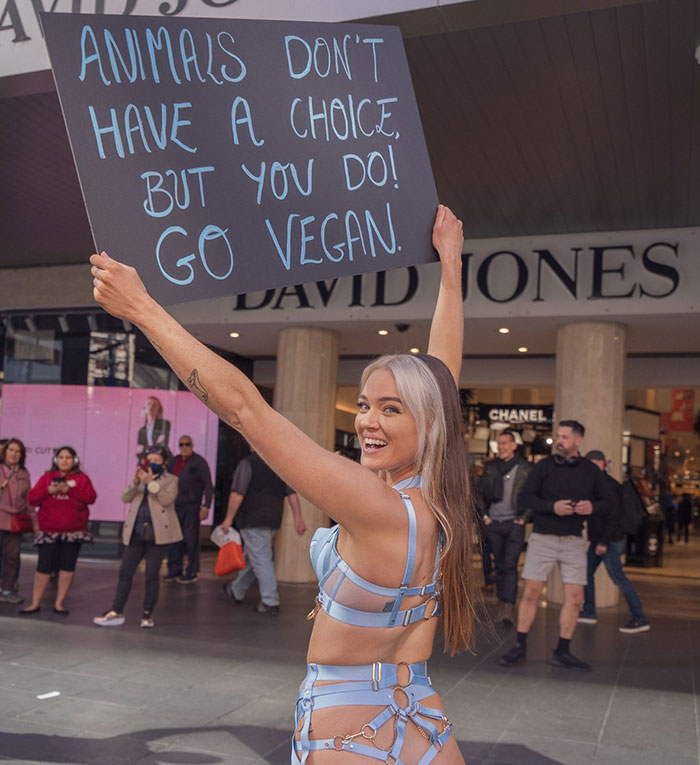 Vegan activist holding a sign promoting animal rights in a public setting. Vegan activist holding a sign promoting animal rights in a public setting.