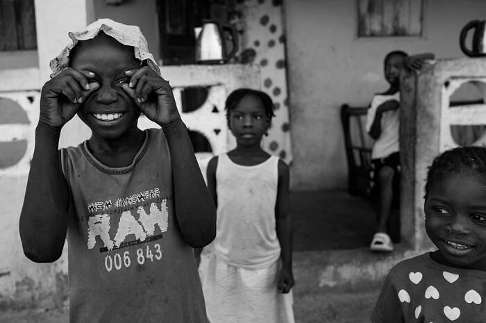 Black-and-white photograph by Ivan Margot showing joyful children playing outside a home.