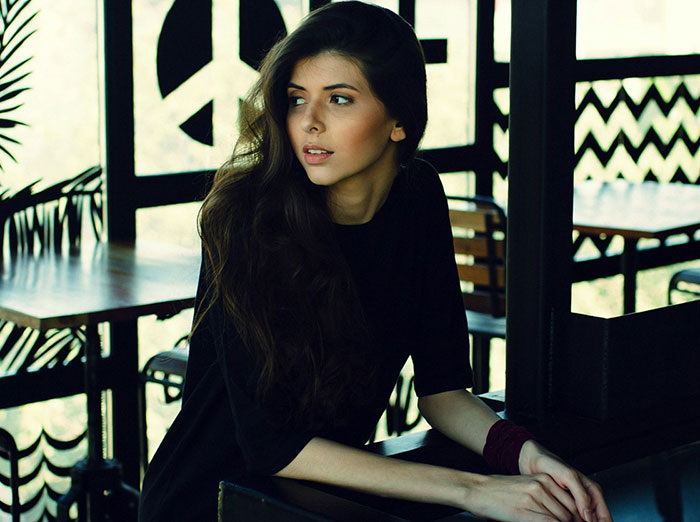 Woman sitting in a dimly lit cafe, looking to the side. Woman sitting in a dimly lit cafe, looking to the side.