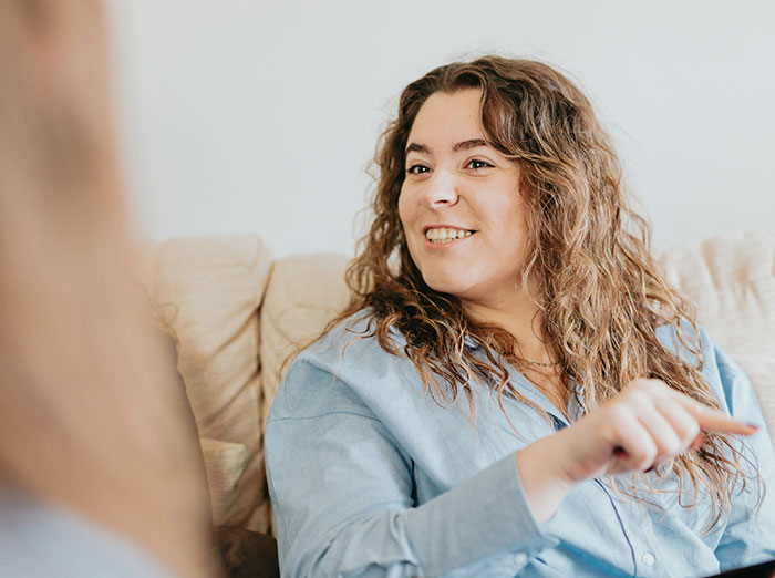 Woman in a blue shirt smiling while sitting, related to exposing a mistress's past. Woman in a blue shirt smiling while sitting, related to exposing a mistress's past.