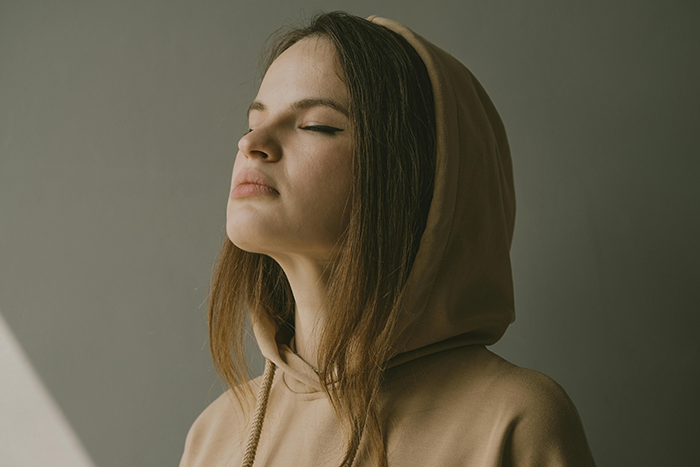Woman in a tan hoodie with closed eyes, reflecting on relationship. Woman in a tan hoodie with closed eyes, reflecting on relationship.