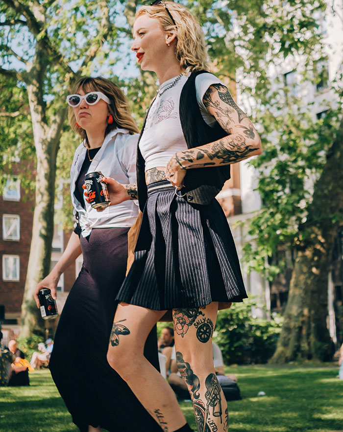 Young people with visible tattoos walking in a park, representing 2024 tattoo trends debate. Young people with visible tattoos walking in a park, representing 2024 tattoo trends debate.