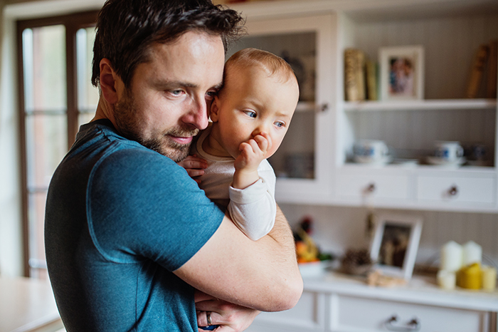 Dad babysits, holding a baby in a cozy kitchen setting. Dad babysits, holding a baby in a cozy kitchen setting.