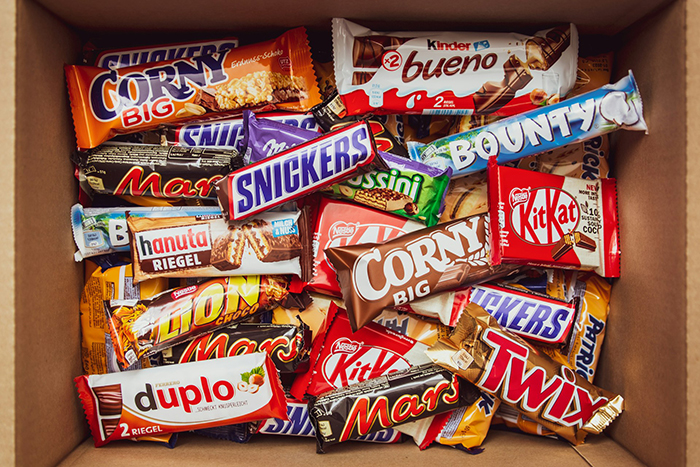 Assorted candy bars in a box, featuring brands like Snickers, Mars, and KitKat. Assorted candy bars in a box, featuring brands like Snickers, Mars, and KitKat.