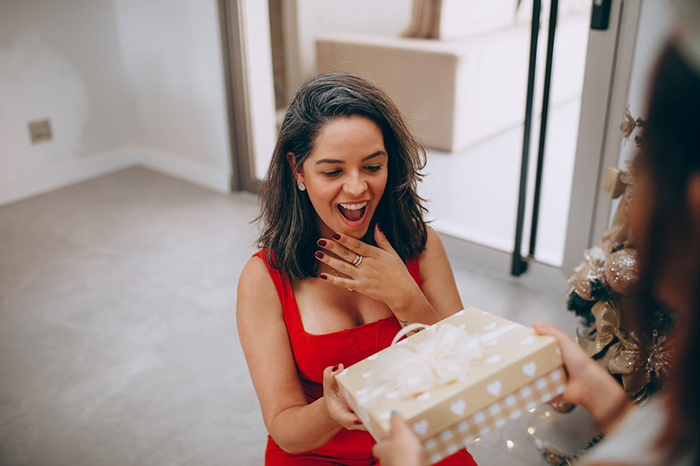 Woman in a red dress receiving a gift, looking surprised and delighted. Woman in a red dress receiving a gift, looking surprised and delighted.