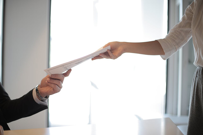 A person handing over documents, highlighting background check issues in the hiring process. A person handing over documents, highlighting background check issues in the hiring process.