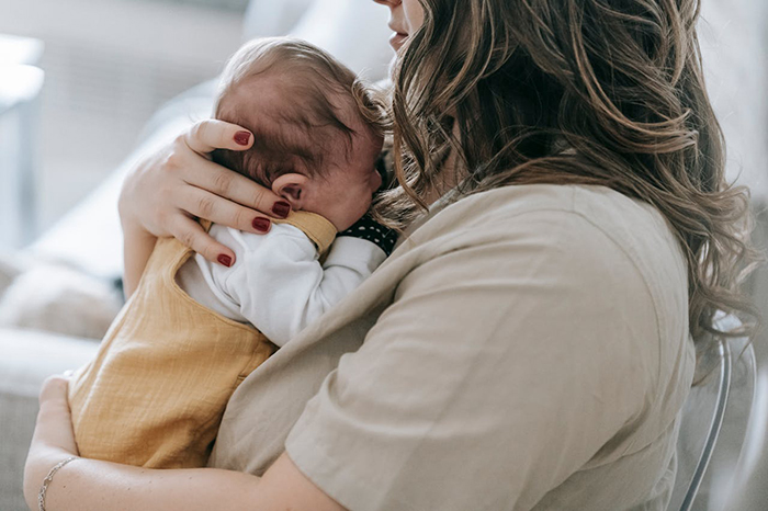 Woman holding a baby, highlighting shared parenting responsibilities during maternity leave. Woman holding a baby, highlighting shared parenting responsibilities during maternity leave.