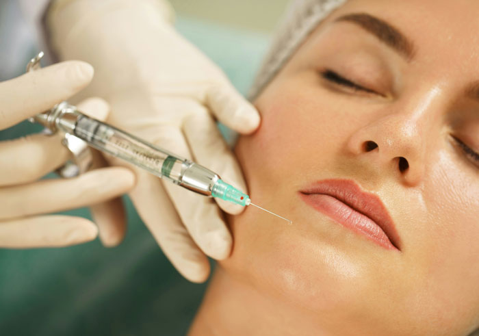 A woman receiving a cosmetic injection, highlighting a criticized fashion trend.