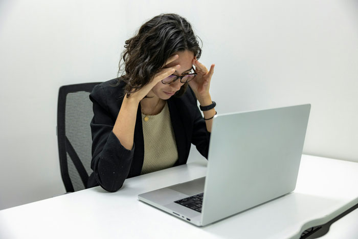 Stressed woman at laptop, troubled by IT sabotage of her career. Stressed woman at laptop, troubled by IT sabotage of her career.