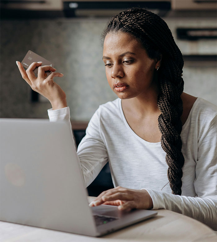 Woman persistently tracking delayed order on laptop, holding a credit card. Woman persistently tracking delayed order on laptop, holding a credit card.