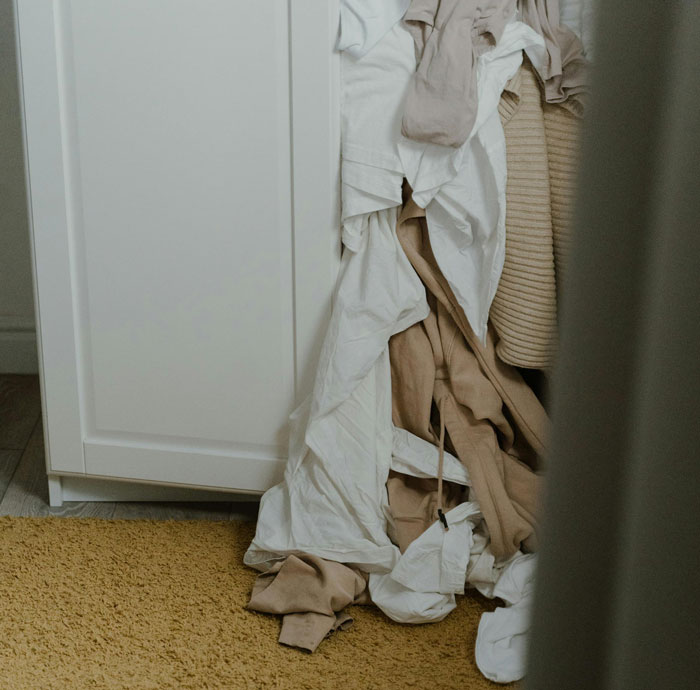 Pile of crumpled clothes next to a wardrobe, illustrating disliked fashion trends.