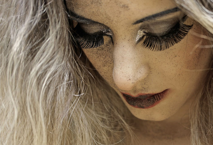 Close-up of a person with heavy makeup and false eyelashes, reflecting controversial fashion trends.