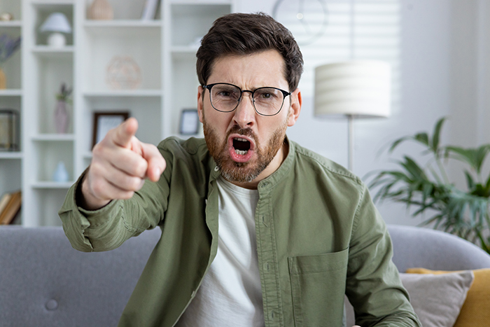 Man expressing anger, pointing finger, possibly during a lying test scenario in a modern living room setting. Man expressing anger, pointing finger, possibly during a lying test scenario in a modern living room setting.
