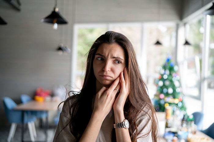 A concerned woman in an apartment with a Christmas tree, highlighting a roommate issue. A concerned woman in an apartment with a Christmas tree, highlighting a roommate issue.