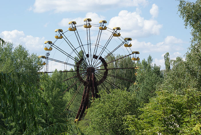 Ferris wheel in Chornobyl area surrounded by dense greenery on a sunny day. Ferris wheel in Chornobyl area surrounded by dense greenery on a sunny day.
