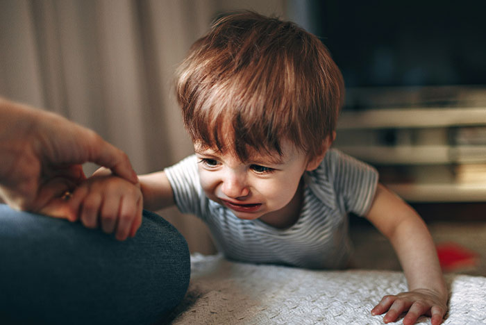 A toddler crying indoors, reaching for a person’s hand, possibly related to a concussion. A toddler crying indoors, reaching for a person’s hand, possibly related to a concussion.