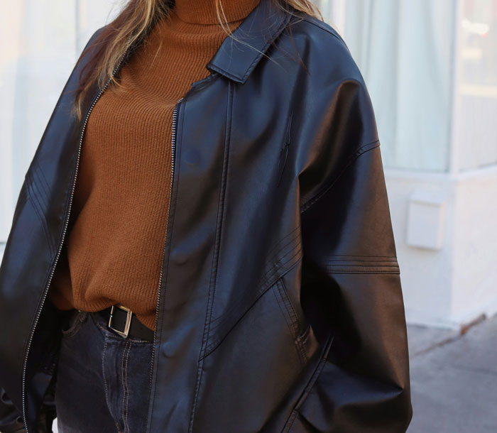 Person wearing an oversized leather jacket and brown turtleneck; fashion trends discussion.
