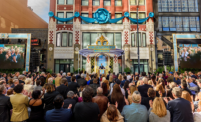Crowd gathered outside the Scientology building, with blue decorations, during a public event. Crowd gathered outside the Scientology building, with blue decorations, during a public event.