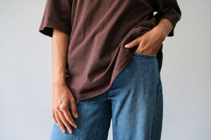 Person wearing a brown shirt and blue jeans, illustrating casual fashion trends.