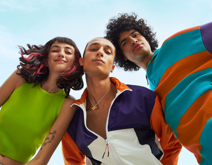 Three people in bold, colorful outfits express playful disapproval of various fashion trends.