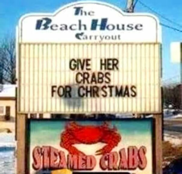 Absurd sign at Beach House Carryout reading "Give her crabs for Christmas" above a steamed crabs illustration.