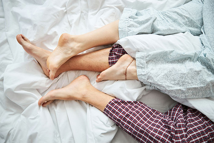 Feet entangled under sheets, symbolizing a cheating girlfriend scenario. Feet entangled under sheets, symbolizing a cheating girlfriend scenario.
