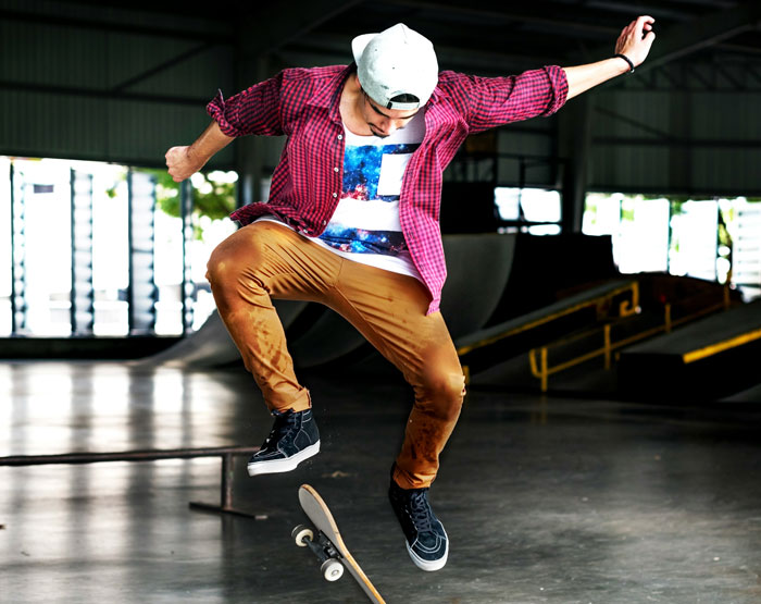 Person skateboarding indoors, wearing a backwards cap, patterned shirt, and tan pants, showcasing fashion trends some dislike.