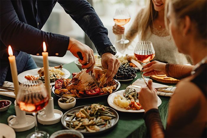 Thanksgiving dinner with family, featuring a turkey being carved and wine glasses raised in a festive atmosphere. Thanksgiving dinner with family, featuring a turkey being carved and wine glasses raised in a festive atmosphere.