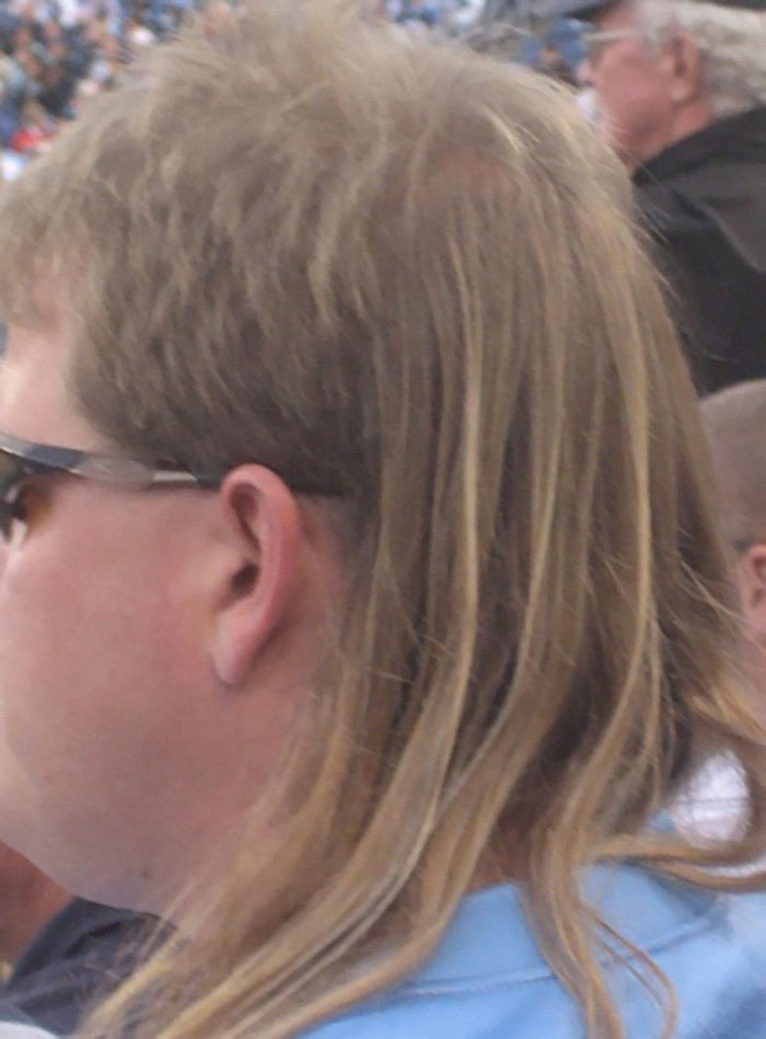Person wearing sunglasses with a mullet hairstyle, a fashion trend openly criticized.