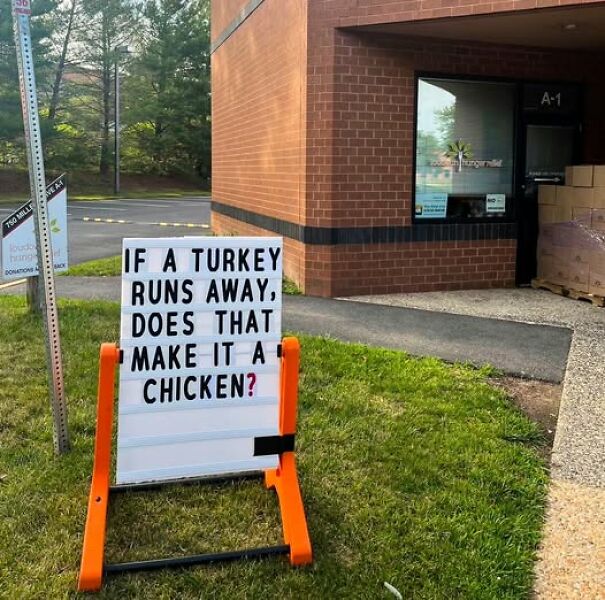Weird sign with humorous question about turkeys and chickens outside a brick building.